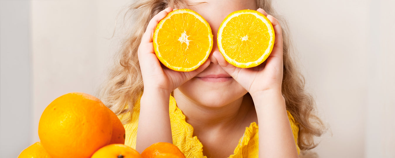 Pikkutyttö leikkii appelsiineilla